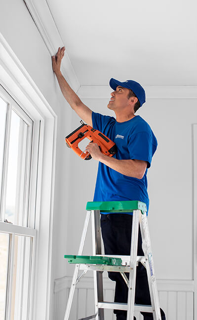 craftsman using nail gun to install crown molding