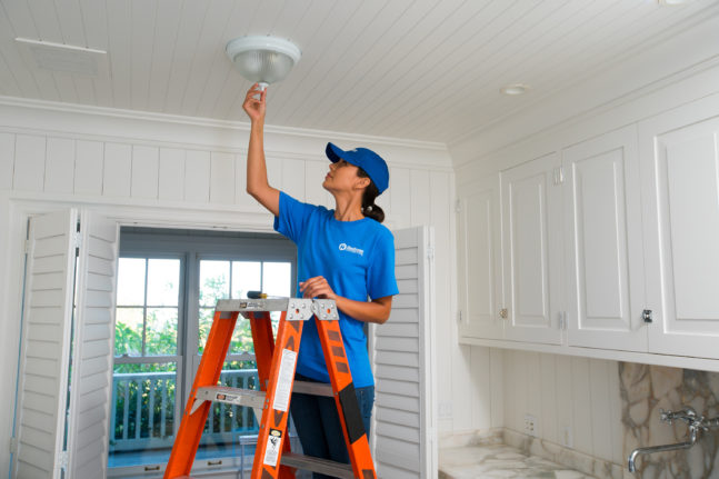 craftsperson installing new electric light fixture on ceiling