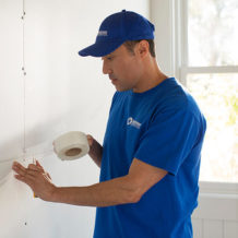 handyman using tape to repair home drywall